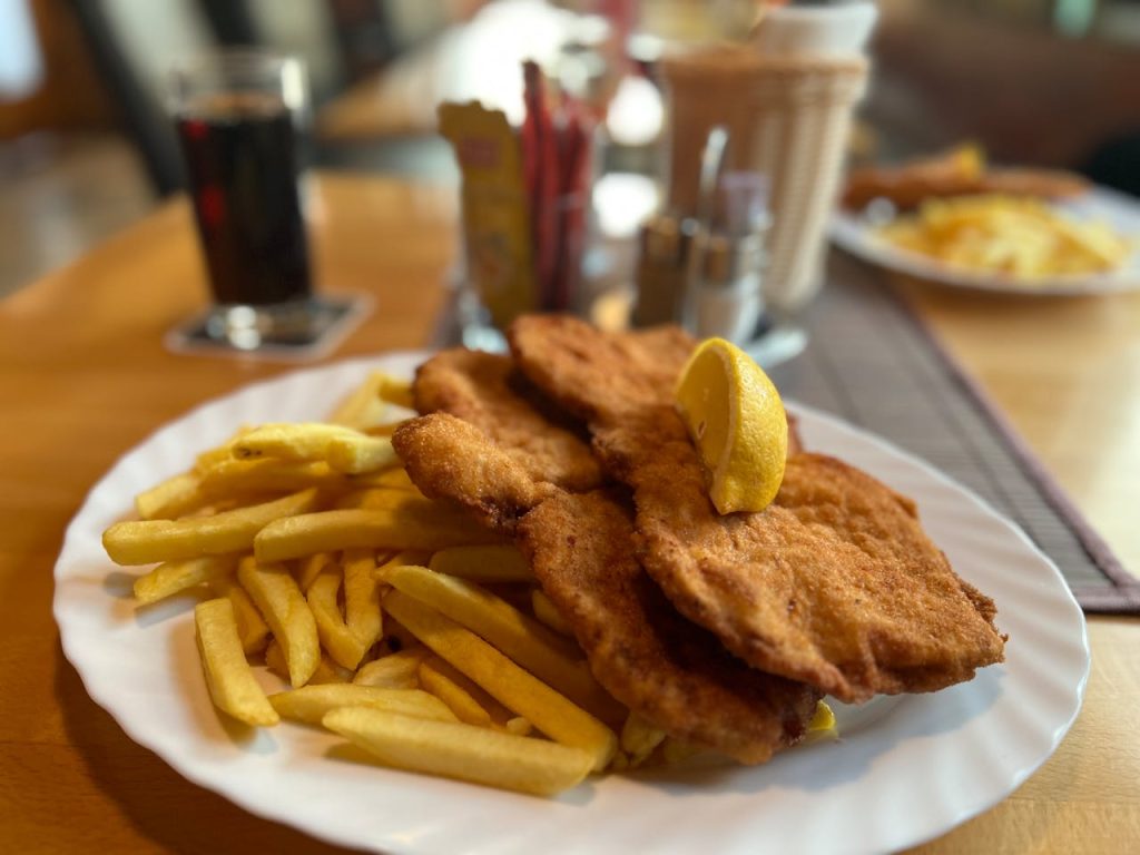 Delicious schnitzel with fries and lemon, served at a cozy restaurant table.